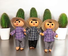 three dolls are standing next to each other in front of cacti