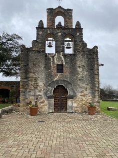 an old church with two bells on it's front door and brick walkway leading up to the entrance