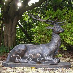 a statue of a deer sitting in front of some trees