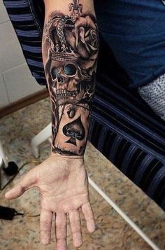 a man's arm with a skull and crown tattoo on the left hand,