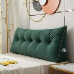 a bed with a green pillow on top of it next to a wall mounted clock