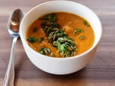 a white bowl filled with soup next to a spoon