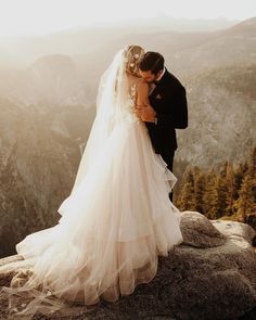 a bride and groom standing on top of a mountain