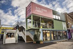 a building made out of shipping containers with stairs leading up to the second floor and windows