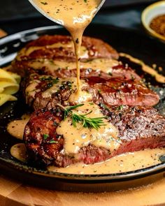 a steak covered in gravy being drizzled with sauce