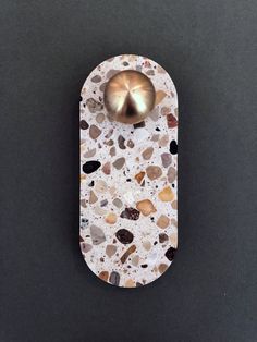 a white and brown object with a metal bell on it's back end sitting on a black surface