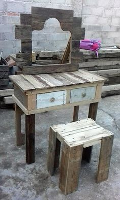 a wooden table with two stools and a mirror on top of it in front of a brick wall