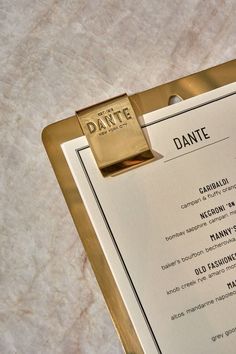 a menu on a clipboard with the name dante in gold and white lettering