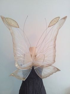 a woman's head wearing a white butterfly wings and black dress with gold accents