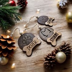 three wooden ornaments with the words dozer and snowman on them next to pine cones