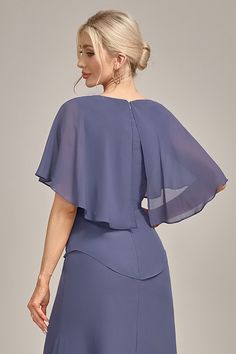 a woman in a blue dress with an open back and cape over her shoulders, looking off to the side