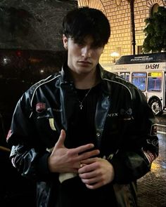 a young man standing in front of a bus holding his hand out to the side