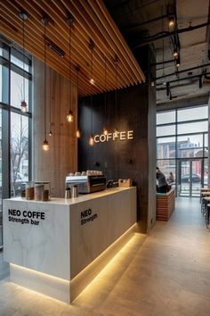 a coffee shop with lots of windows and lights on the ceiling, along with a counter