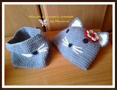 two crocheted hats with cats on them sitting on top of a wooden table