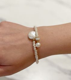 a close up of a person wearing a bracelet with pearls