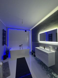 a modern bathroom with blue lights on the wall and tub in the center, along with two sinks