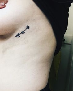 a woman's stomach with a small flower tattoo on her left side ribcage