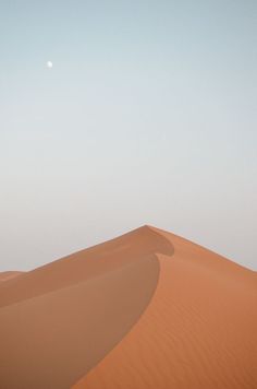 a person walking across a desert with a full moon in the sky behind them,