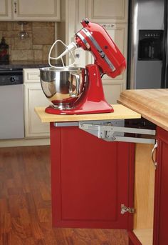 a red mixer sitting on top of a wooden counter