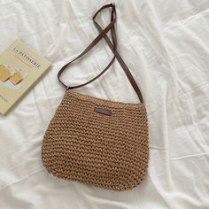 a brown purse sitting on top of a bed next to a book