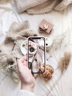 a person taking a photo with their cell phone while sitting on a bed covered in blankets