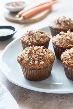 several muffins on a white plate with carrots and yogurt in the background