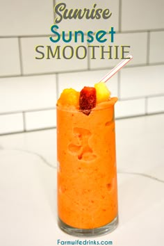 an orange smoothie in a glass with strawberries and pineapples on top