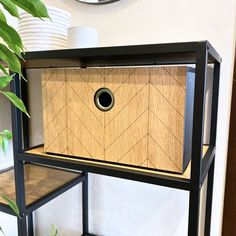 a black shelf with a wooden box on it next to a potted plant and a clock