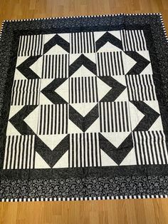 a black and white quilt is laying on the floor next to a wooden table top