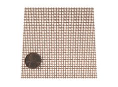 a penny sitting on top of a piece of metal mesh