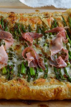 a pizza with asparagus, ham and cheese on it