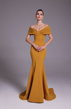 a woman in an off the shoulder yellow dress standing with her hands on her hips