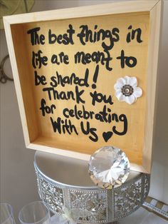 a wooden box with writing on it and some wine glasses in front of the frame