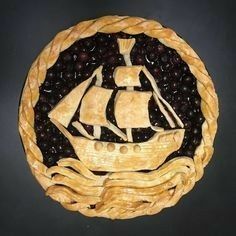 a pie with a sailboat on it and blueberries in the bottom crusts