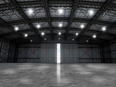 an empty warehouse with bright lights on the ceiling and concrete floor in front of it