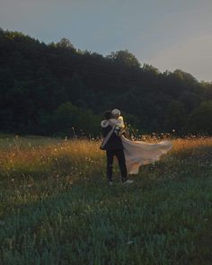 a man and woman are standing in the grass with their arms wrapped around each other