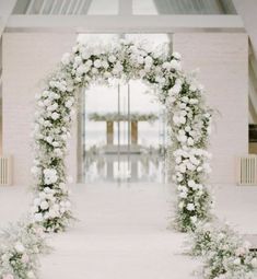 an archway decorated with white flowers and greenery