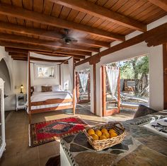 a bed room with a neatly made bed and a basket of fruit