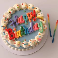 a birthday cake with the words happy birthday written on it and two colored candles next to it