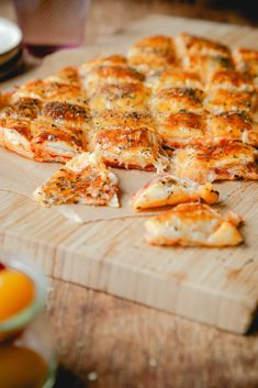 a pizza sitting on top of a wooden cutting board next to slices of pizza in front of it