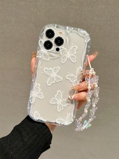 a person holding a clear case with white flowers on it and beads hanging from the side