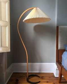 a floor lamp sitting on top of a wooden table next to a bed in a room