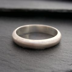 The Matte Band is a unisex ring featuring an opaque, brushed finish. A truly timeless & classic design, that will never go out of style, and is perfect for everyday wear. This design is part of The Masculine Bands collection, which are a popular choice among men venturing into the world of rings for the first time. Its comfort and ease of wear make it an excellent option for those new to wearing jewelry, or simply for people who love the simple and classic aesthetic.This band looks great when st Classic Anniversary Rings With Brushed Finish, Classic Anniversary Ring With Brushed Finish, Simple Wedding Bands, Wearing Jewelry, Wedding Band Designs, Jewelry Staples, Classic Aesthetic, Plain Bands, Unisex Ring