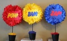 three paper pom poms sitting on top of each other in front of a wall