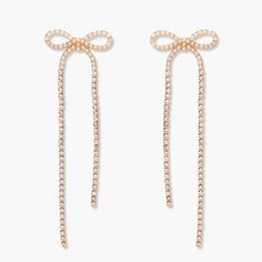 Add a touch of sparkle to any outfit with the Adeline Bow Statement Earring. This unique earring features a pearl bow design with delicate rhinestone chains, making it the perfect statement piece for any occasion. Stand out with this playful and fun accessory! Available in 14k gold plated base Pearl Bow: 22mm Rhinestone Chains: 39mm and 57mm Stainless steel post with friction back Protected with an anti-tarnish barrier SKU: BYE1188 Chic Rhinestone Earrings For Gift, Trendy Party Jewelry With Decorative Bow, Evening Dangle Jewelry With Bow Detail, Glamorous Evening Jewelry With Bow Detail, Glamorous Evening Jewelry With Bow, Party Bow Earrings In Metal, Bow Detail Drop Earrings For Party, Trendy Bow Earrings For Party, Trendy Party Earrings With Bow