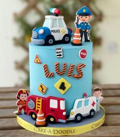 a blue cake decorated with cars, firetrucks and police figures