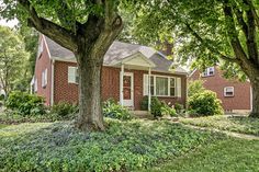 a red brick house surrounded by trees and bushes