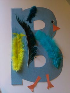 the letter b is made out of paper with feathers on it and another bird next to it