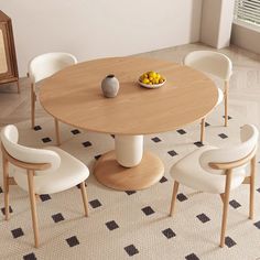 a dining room table with four chairs and a bowl of fruit on the table in front of it