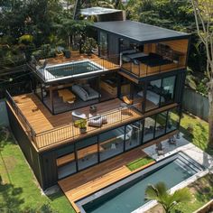 an aerial view of a modern house with pool and decking in the foreground